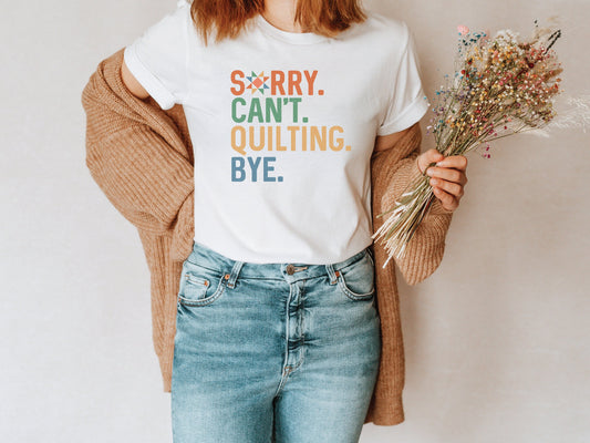 The (distressed style) text on this ladies t-shirt reads Sorry Cant Quilting Bye. Each word has a colorful color text (Orange, Green, Yellow and Blue). Quilt star in the O in Sorry.